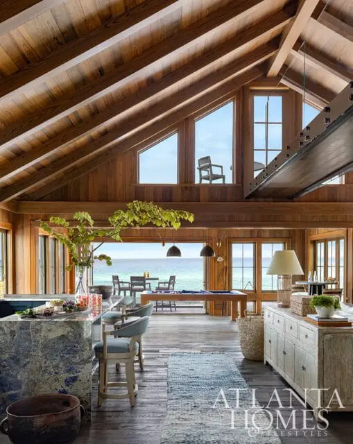 Wood-paneled room with vaulted ceiling, ocean view, marble island, and distressed buffet