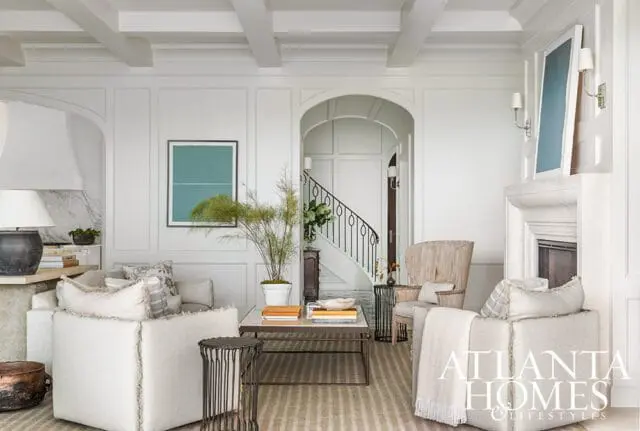 Living room with white paneled walls, coffered ceiling, fireplace, and staircase.