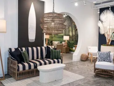 Living room with striped sofa, rattan chairs, and forest mural