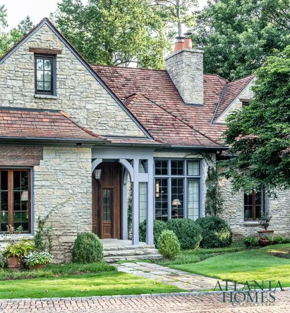 Stone house with red tile roof, arched entryway, and manicured lawn.