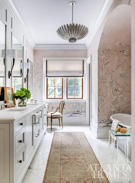 White double vanity, pink floral wallpaper, and clawfoot tub in a bathroom.