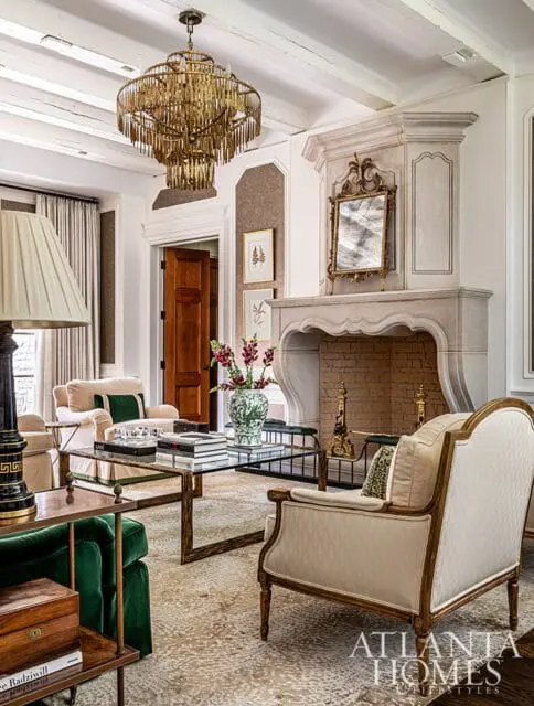 Living room with ornate gold chandelier, fireplace, and upholstered furniture.