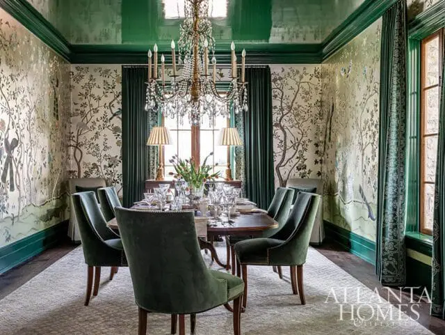 Dining room with green velvet chairs, chinoiserie wallpaper, and a crystal chandelier.