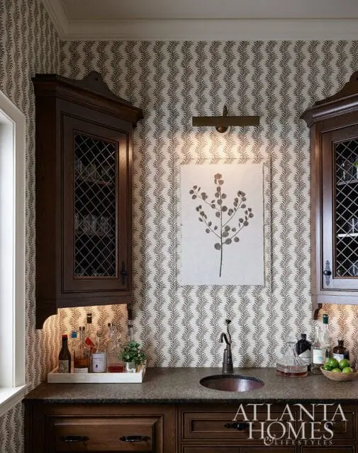 Bar area with dark wood cabinets, patterned wallpaper, and a copper sink.