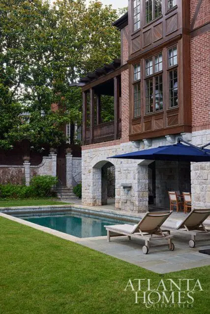 Brick and stone house with wooden bay window, covered porch, and swimming pool.