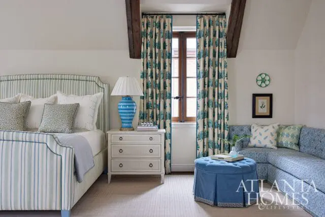 Bedroom with striped bed, blue patterned sofa, and floral curtains