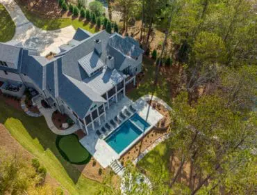 Modern home with gray metal roof, pool, putting green, and lake view