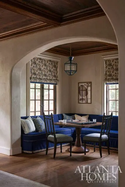 Blue banquette seating with patterned roman shades and a wooden table