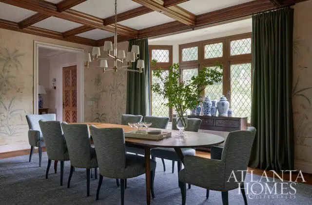 Dining room with botanical wallpaper, coffered ceiling, oval table, and upholstered chairs.