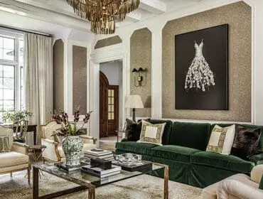 Living room with green velvet sofa, ornate chandelier, and artwork of a white dress.