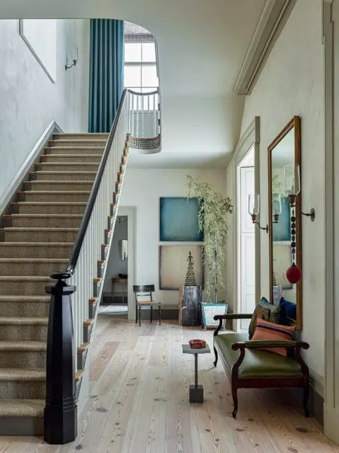 Hallway with carpeted staircase, green bench, and mirror.