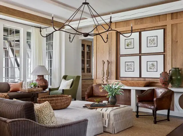 Living room with wood paneled walls, four framed botanical prints, and rustic furniture.