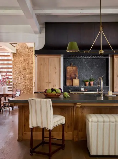 Kitchen island with striped stools, dark countertop, and wood cabinetry.