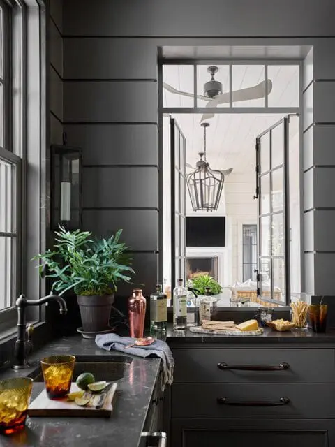 Dark gray kitchen with marble countertops, copper shaker, and view to patio