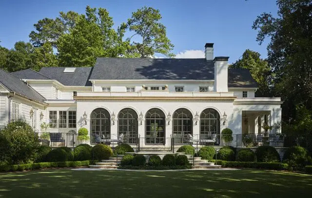 White Classical Revival home with arched windows and manicured hedges