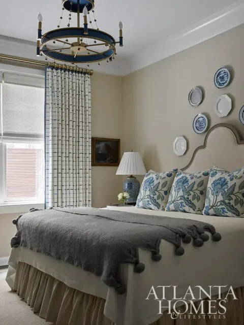 Bedroom with blue and white floral pillows, gray throw, and blue chandelier.