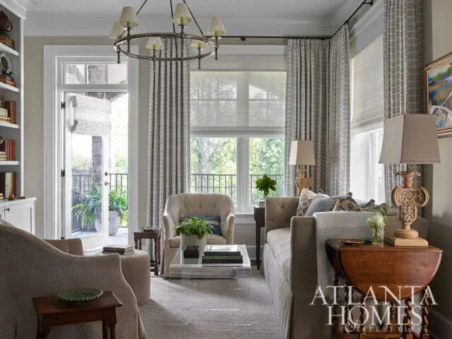 Living room with neutral upholstered furniture, patterned curtains, and a circular chandelier.