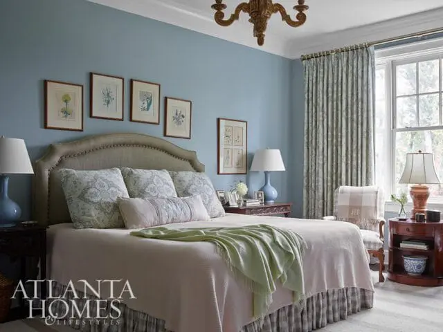 Blue bedroom with upholstered headboard, patterned pillows, and light pink bedding.