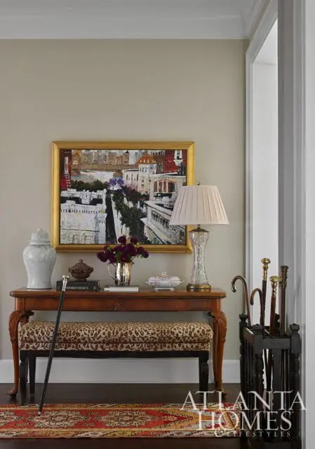 Entryway with console table, leopard print bench, painting, and umbrella stand