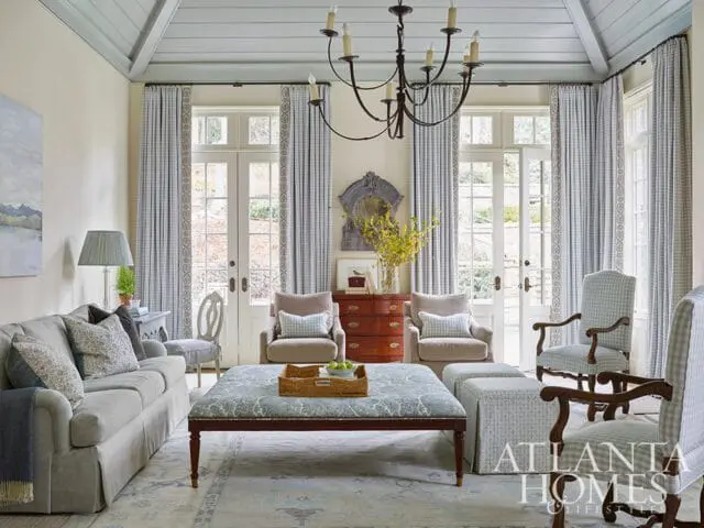 Living room with blue and white checkered chairs, patterned ottoman, and French doors.