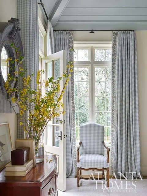 Blue gingham armchair in front of a window with matching curtains.