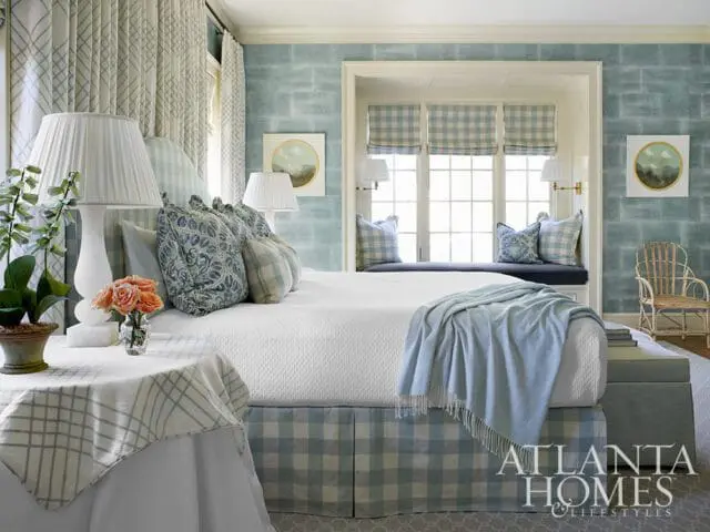 Bedroom with blue and white buffalo check accents, textured blue wallpaper, and a window seat.