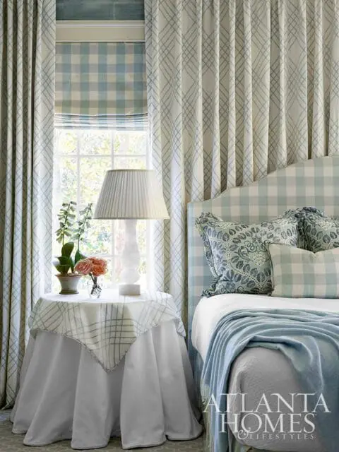 Bedroom with blue and white gingham headboard, patterned pillows, and plaid curtains.