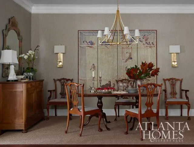Dining room with antique wooden chairs, a dark wood table, and a large birdcage painting.