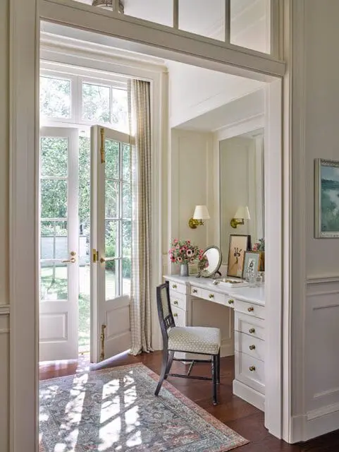 Cream vanity with marble top, ornate chair, and French doors opening to garden.