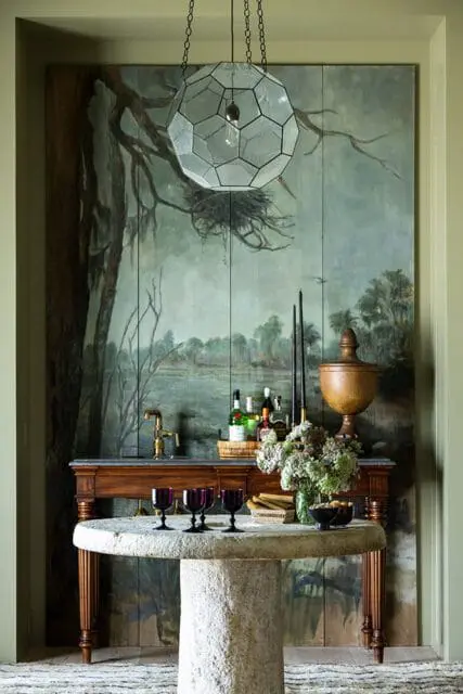 Bar area with dark wood cabinet, marble countertop, and stone pedestal table with purple glasses.