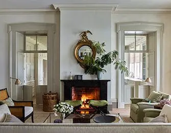 Living room with fireplace, ornate mirror, and two armchairs.