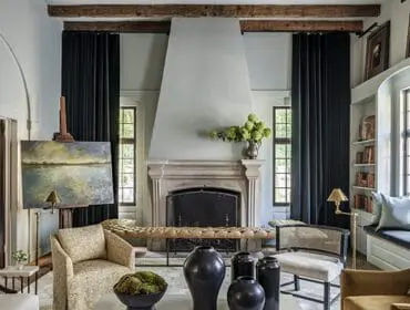 Living room with stone fireplace, tufted bench, artwork, and bookshelves