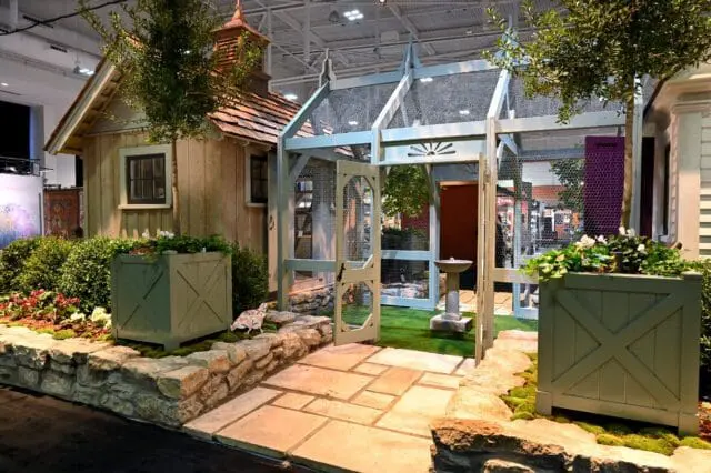Wooden chicken coop with a stone pathway and planters.