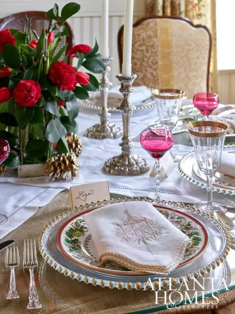 Table setting with floral plates, embroidered napkins, and pink wine glasses.