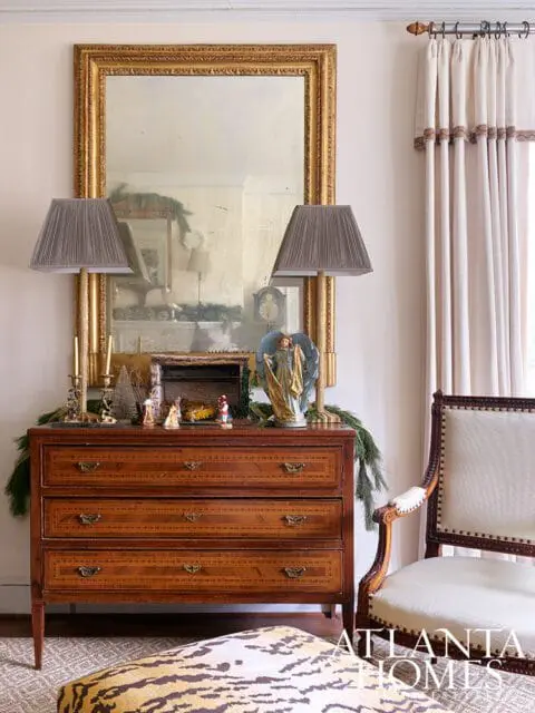 Wooden dresser with mirrored wall, two lamps, and Christmas decorations