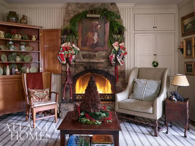 Living room with stone fireplace decorated for Christmas, featuring stockings, a dog portrait, and