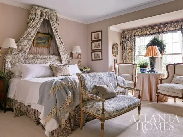 Bedroom with a canopy bed, floral curtains, and a patterned bench.