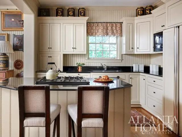 Cream kitchen with beadboard walls, black granite counters, and a gas range.