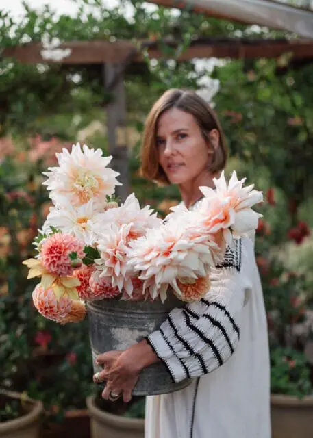 Woman holding a bucket of pale pink and yellow dahlias