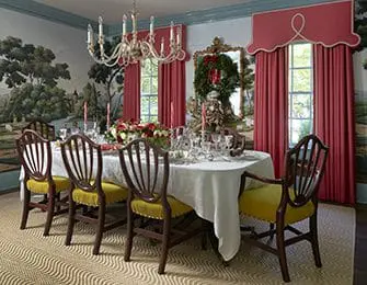 Dining room with a long table set for a meal, flanked by chairs with yellow upholstery and dark