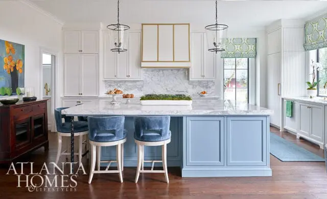 White kitchen with marble island, blue island base, and blue velvet bar stools.