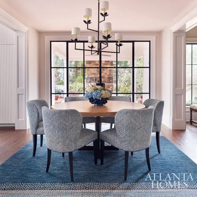 Dining room with oval wood table, blue patterned chairs, and large window.
