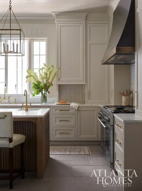 Kitchen with light gray cabinets, brass hardware, and a dark metal range hood.