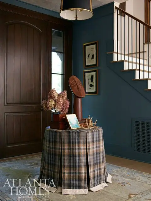 Entryway with dark wood door, plaid skirted table, and blue walls