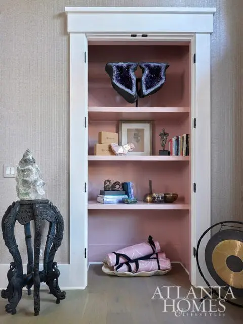 Pink shelves with amethyst geode, books, and yoga mats. Atlanta Homes & Lifestyles logo.