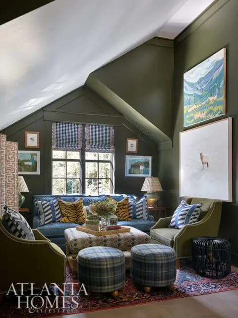 Living room with olive green walls, blue sofa, plaid ottomans, and artwork
