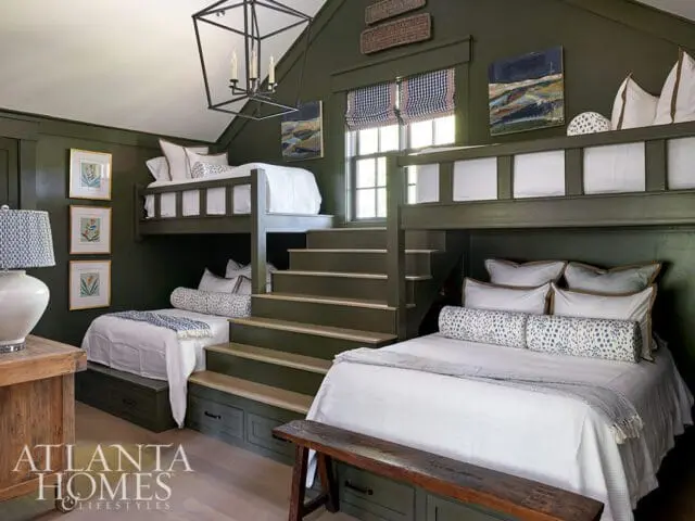 Dark green bedroom with built-in bunk beds, stairs, and white bedding.