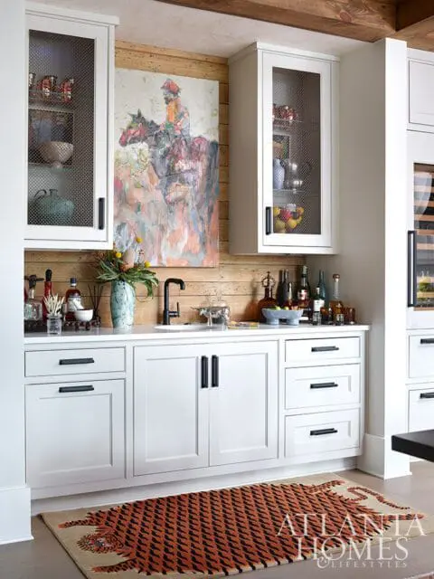White bar with a painting of a rider on a horse, wood paneled wall, and tiger rug.