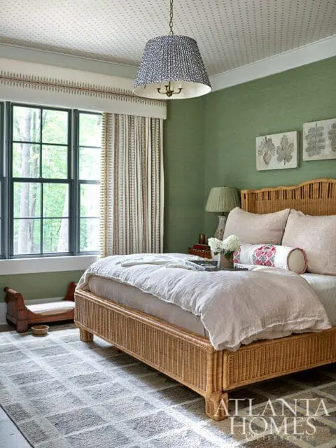 Bedroom with green grasscloth walls, wicker bed, and patterned ceiling