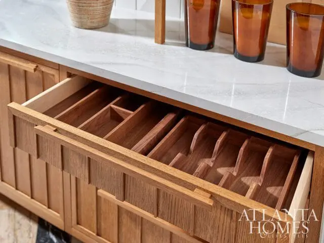 Wooden kitchen drawer with built-in cutlery organizer and fluted wood cabinet doors